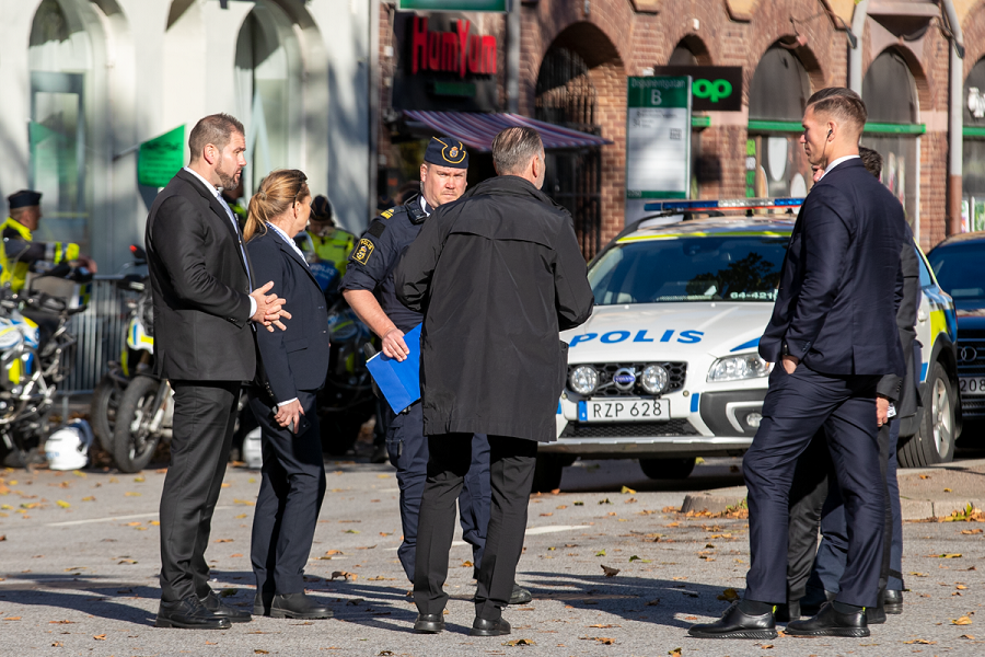 Livvakter och poliser samtalar utomhus.